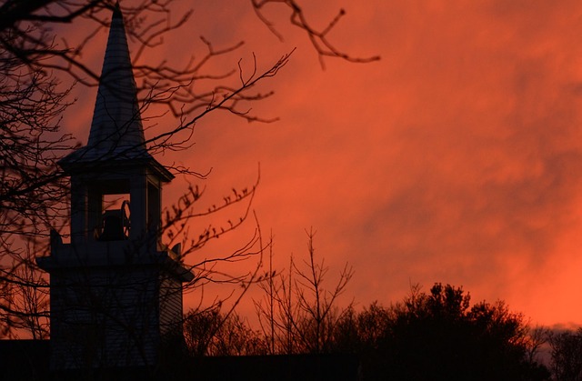 Orange sunset over the spire of a house.